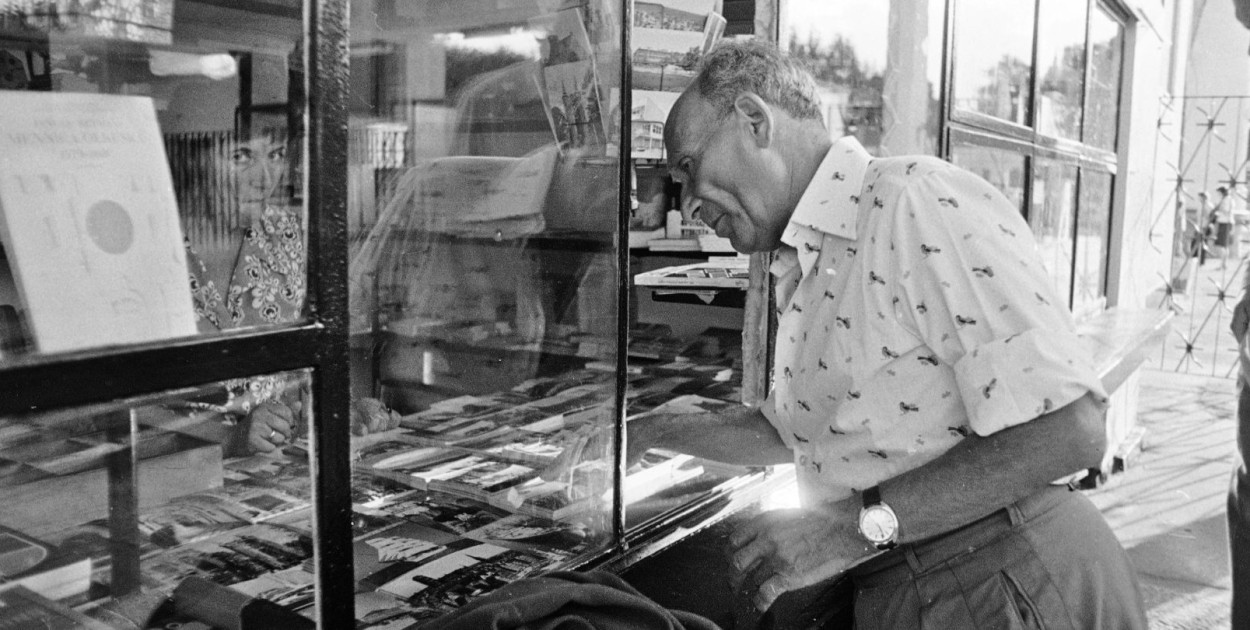 Pisarz Julian Stryjkowski stoi przy kiosku z pocztówkami w Sopocie, 1975 r. Fot. Włodzimierz Barchacz. Źródło: Narodowe Archiwum Cyfrowe