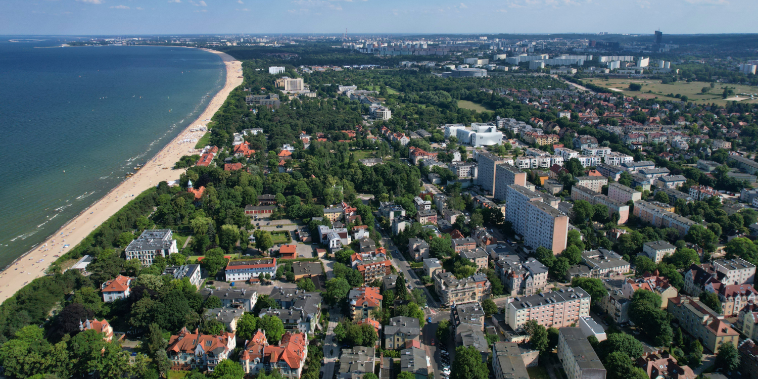 Ceny mieszkań w Sopocie. Na zdjęciu: widok z drona na morze, plażę i nadmorskie ulice Sopotu.